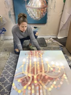 a woman is working on an art project with lights in the shape of a chandelier