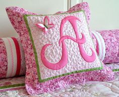 pink and green decorative pillows on a bed