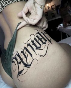 a woman is showing off her thigh with the word tattoo on it's side