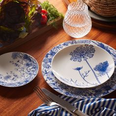 plates and utensils are sitting on a wooden table with blue striped napkins