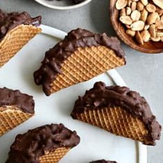 chocolate covered waffles on a plate next to nuts