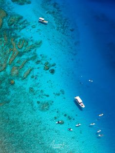 several boats floating on the water near some coral reefs