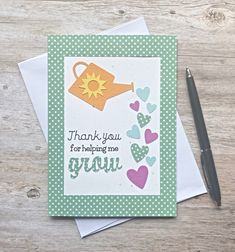 a thank you card with hearts and a watering can on it next to a pen