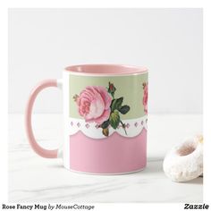 a pink coffee mug sitting next to a donut