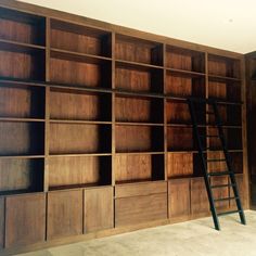 an empty room with wooden shelves and ladder