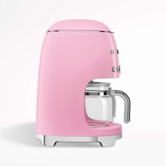 a pink coffee maker sitting on top of a white table