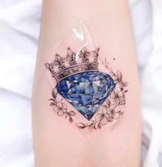 a woman's leg with a blue diamond tattoo on it and a crown in the center