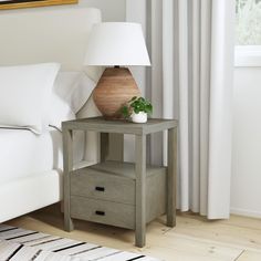 a nightstand with a lamp on it next to a bed