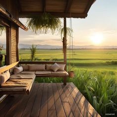 a wooden porch with a swing chair and pillows on it, overlooking an open field