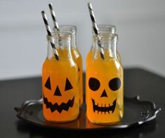 two bottles filled with orange liquid decorated like jack - o'- lanterns