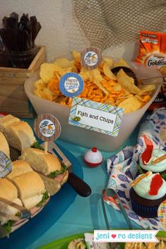 a table topped with lots of sandwiches and cupcakes