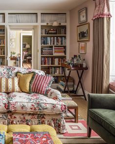 a living room filled with lots of furniture and bookshelves covered in colorful pillows