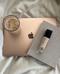 an apple laptop and drink on a bed