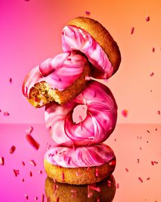 two donuts with pink icing and sprinkles are stacked on top of each other