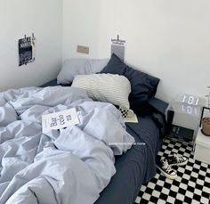 an unmade bed sitting in a bedroom next to a black and white checkered floor