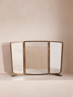 a mirror sitting on top of a wooden table next to a white wall and floor