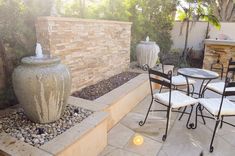 a patio area with chairs, table and fountain