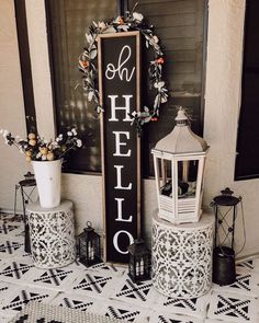 a black and white sign that says welcome to the front of a house with flowers on it