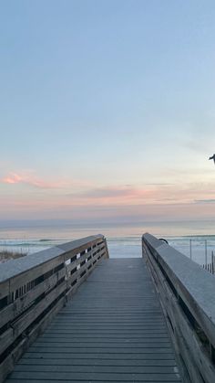 a wooden walkway leading to the beach at sunset