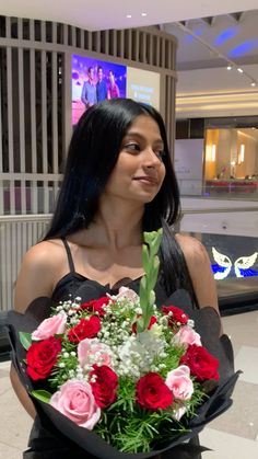 a woman holding a bouquet of flowers in her hands at an airport or shopping center