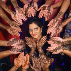 a woman is surrounded by hands with henna on her