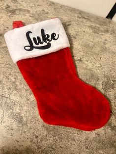 a red christmas stocking with the word luke on it sitting on a counter top