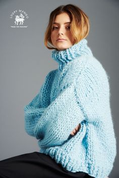 a woman in a blue sweater is posing for the camera with her hands on her hips