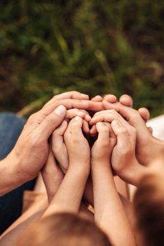 several people holding their hands together to form a heart with their hands over each other