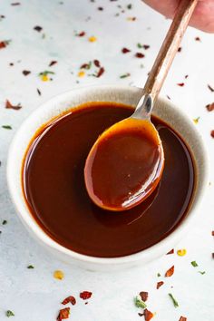 a spoon full of caramel sauce in a white bowl