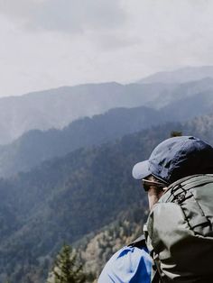 a man sitting on top of a mountain looking out at the mountains in the distance