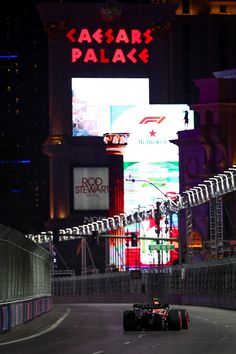 a man driving a race car down a street in front of a tall building at night