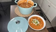 two bowls of soup are sitting on a wooden table in front of the stove top