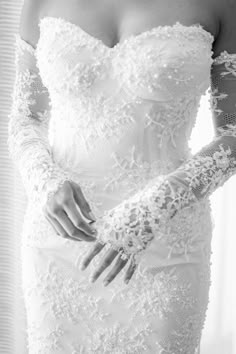 black and white photo of woman in wedding dress with gloves on her arm, looking off to the side