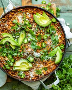 a skillet filled with mexican food and topped with avocado