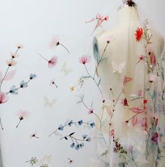 a white dress with flowers on it next to a mannequin