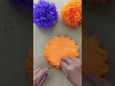 someone is making paper flowers out of orange and purple pom - poms