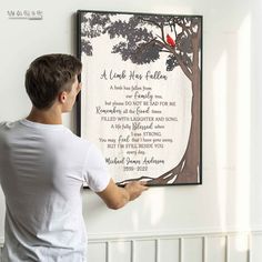 a man is holding up a framed poem on the wall with a red bird perched on it