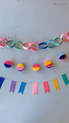 paper streamers and buntings are hanging on the wall in front of a white table