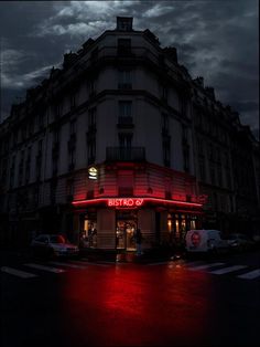 a building that has red lights on the side of it and cars parked in front