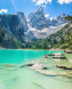 a person on a kayak in the water near mountains