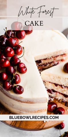 a cake with white frosting and fresh cherries on the top is cut in half