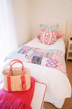 a bedroom with a white bed, pink rug and colorful pillows on top of it