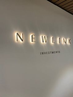 the neon sign for newlink investments hangs on the wall in front of it's entrance