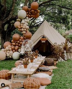 an outdoor tent set up for a party with balloons and other decorations on the grass