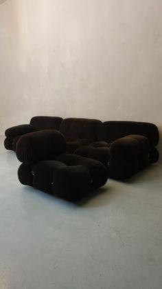 a large black couch sitting on top of a floor next to a white wall in an empty room