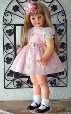 the doll is wearing a pink dress and black shoes