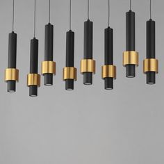 a group of black and gold pendants hanging from a gray ceiling with white walls in the background