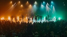 a group of people standing on top of a stage with lights in the dark behind them