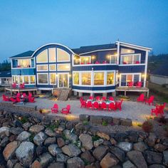 an outdoor dining area with red chairs and tables next to a large building at dusk