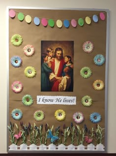 a bulletin board decorated with paper flowers and an image of jesus surrounded by his children